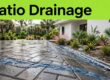 Wet pavers slope toward a linear drain and planted swale beside a Florida home.
