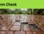 Wet patio pavers have a washed-out joint, scattered leaves, and puddles near a drain.