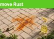 An orange rust mark on brick pavers beside a scrub brush and cleaner.